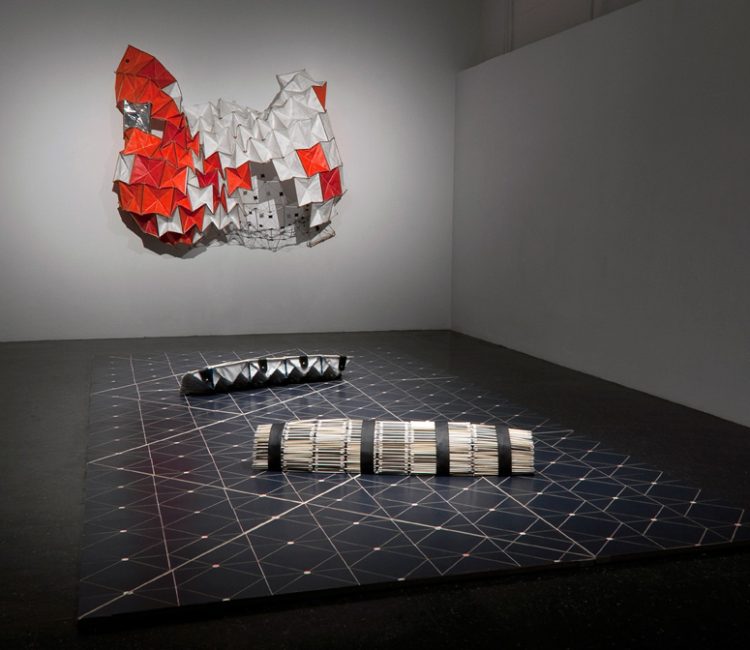 Modular Envelopes, 2013 developed from a desire to create portable instruments that could define a space anywhere. The installation features a room-size wooden game board whose inscribed pattern suggests schematic diagrams, sacred geometry, or abstract blueprints for a trio of modular envelopes that rest collapsed on the floor, or expanded on the wall. Large-scale yet lightweight, the modular envelope is meant to be carried and transformed by a single person. The space created by the interaction can change, depending on one’s body and position in the landscape or gallery. In exhibitions, viewers are welcome to investigate the instruments by scheduling an appointment with the artist.